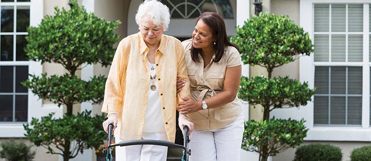 A caregiver is helping an old lady with the walker